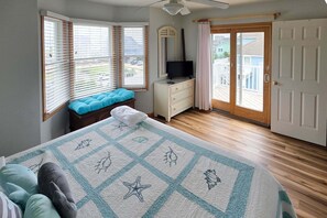 A bedroom with a bed, a dresser, a television, and a view of the outside. - 7853 - Anchor Management Spacious 6BR, 5.2BA oceanside home in Frisco for up to 12 guests. (Frisco)