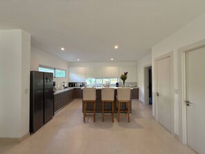 Una cocina moderna con una isla central, un refrigerador y un comedor con sillas.