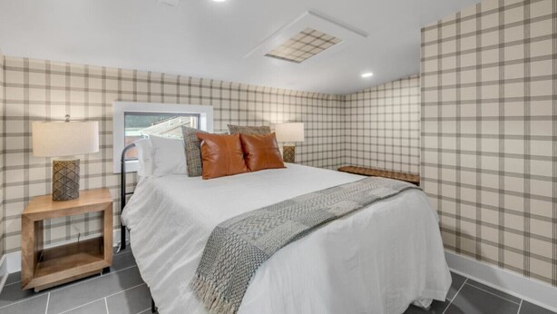 A bedroom with a bed, two bedside tables, a window, and a ceiling light. - Rooftop | Fire pit | Luxury | Sleeps 10 | (Cincinnati)