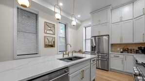 A modern kitchen with stainless steel appliances, white cabinetry, and pendant lighting. - Rooftop | Fire pit | Luxury | Sleeps 10 | (Cincinnati)
