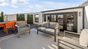 A rooftop patio with outdoor seating, a sofa, and a sliding glass door leading to an indoor space. - Rooftop | Fire pit | Luxury | Sleeps 10 | (Cincinnati)