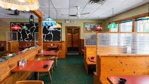 Un restaurante con mesas, cabinas y varios candelabros colgantes.