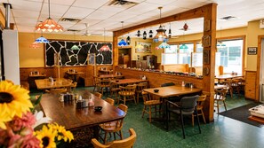 A restaurant interior with wooden tables, chairs, and hanging lamps.