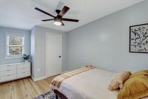 A bedroom with a bed, a ceiling fan, a window with blinds, a bedside table, and a wall-mounted artwork. - 2bd/1ba Cottage * Renovated * Dogs Welcome (Savannah)