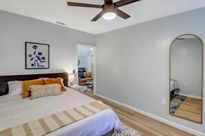 A bedroom with a bed, a ceiling fan, a large mirror, and a painting on the wall. - 2bd/1ba Cottage * Renovated * Dogs Welcome (Savannah)