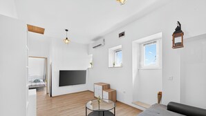 A modern living room with a sofa, a glass coffee table, a TV, and a wooden cabinet. - Apartment Gracija  2-Bedroom Apartment in Dubrovnik Old Town
 (Dubrovnik)