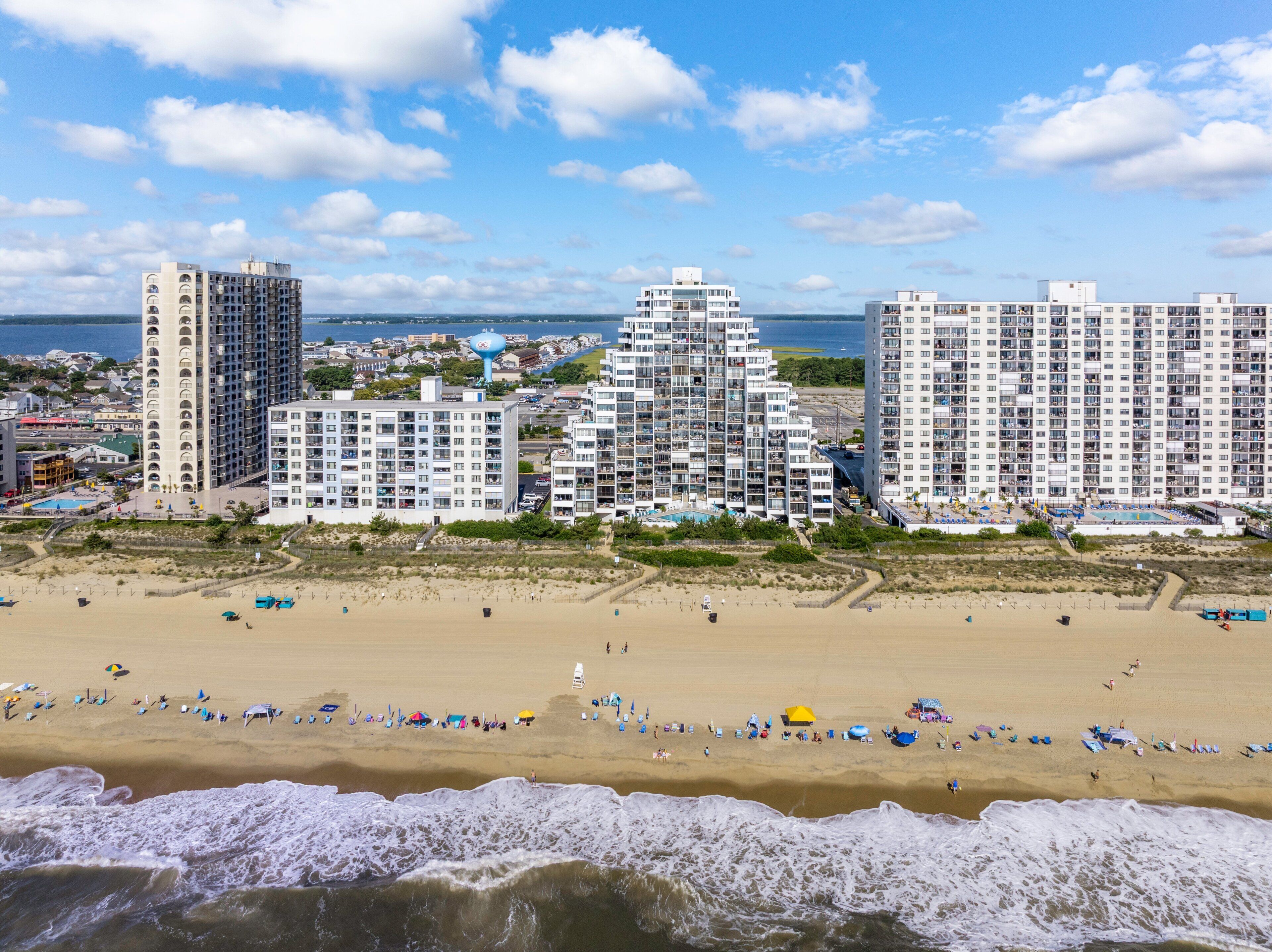 A coastal cityscape with high-rise buildings, a sandy beach, and a view of the ocean.