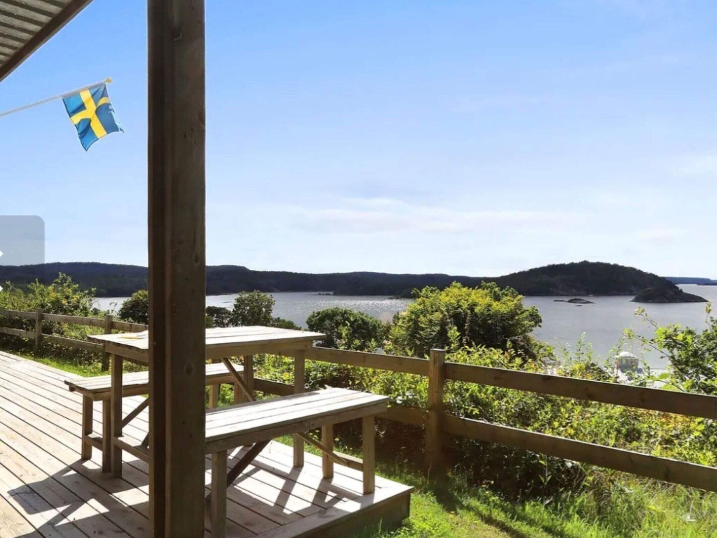 A wooden deck with picnic tables overlooking a lake and hills.