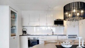 A modern kitchen with white cabinets, a stainless steel oven, a coffee maker, and a chandelier. - 5 Star Holiday Home in Uddevalla (Uddevalla)