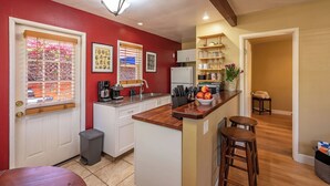 Una cocina con armarios blancos, encimera de madera y una pequeña isla con taburetes.