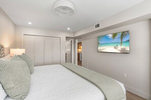 Ein Schlafzimmer mit einem Bett, einem Strandbild, einem Kleiderschrank und einer Tür zu einem Badezimmer.