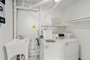 Een wasserette met een wasmachine, een wasbak en een bord met wasinstructies.