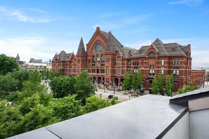 A large, historic red brick building with multiple towers and a prominent clock tower. - Walk to TQL | Music Hall Rooftop View | Fire Pit (Cincinnati)