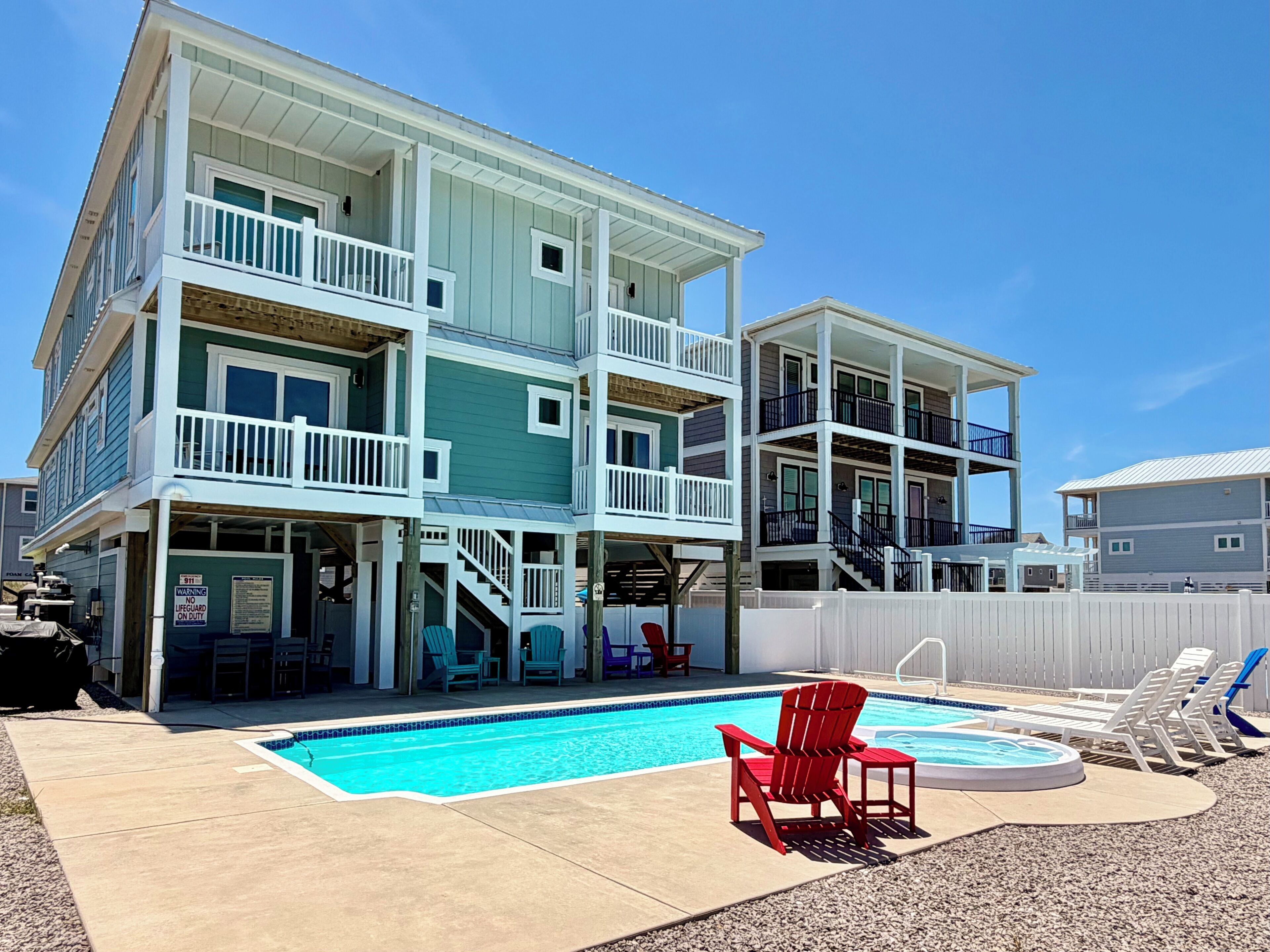 A multi-story building with a pool, outdoor seating, and a lifeguard warning sign.