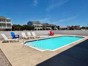 A swimming pool with lounge chairs, a red chair, and a white fence. - Weekend Rescue: 10BR 10.5BA, Ocean Views, Pool, Hot Tub, Elevator, Dog Friendly, Sleeps 22 (Oak Island)