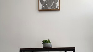A minimalist room with a dark metal table, two matching chairs, a small potted plant, and a framed cactus artwork on the wall. - Cozy 1-bedroom studio in charming Inglewood with AC (Inglewood)