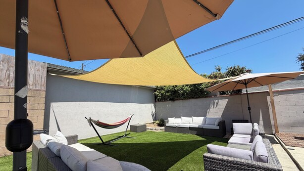 A backyard with artificial grass, wicker furniture, and a hammock. - Cozy 1-bedroom studio in charming Inglewood with AC (Inglewood)