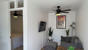 A room with a bed, a ceiling fan, a sofa, a coffee table, and a poster on the wall. - Cozy 1-bedroom studio in charming Inglewood with AC (Inglewood)