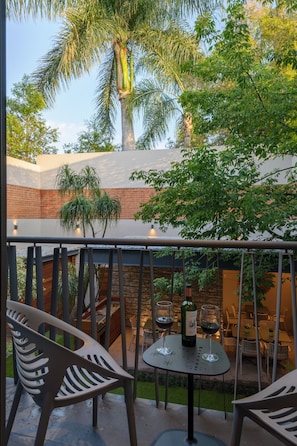 A balcony with chairs, a table, and a bottle of wine.