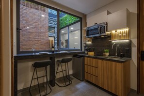 Una cocina moderna con microondas integrado, taburetes de bar y una ventana con vistas a la vegetación.