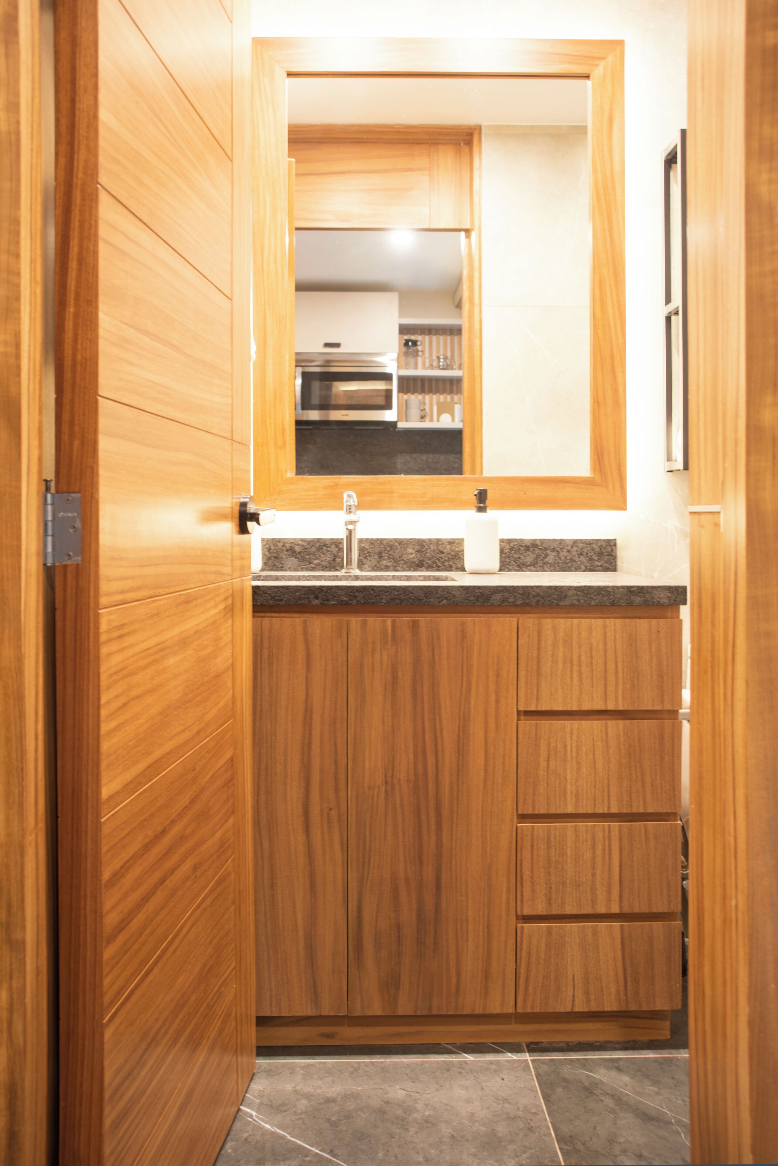 Un baño de madera con lavamanos, espejo y armarios.