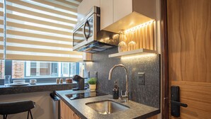 A modern kitchen with a built-in microwave, stainless steel sink, and a bar stool. - Casa Makech (Zapopan)
