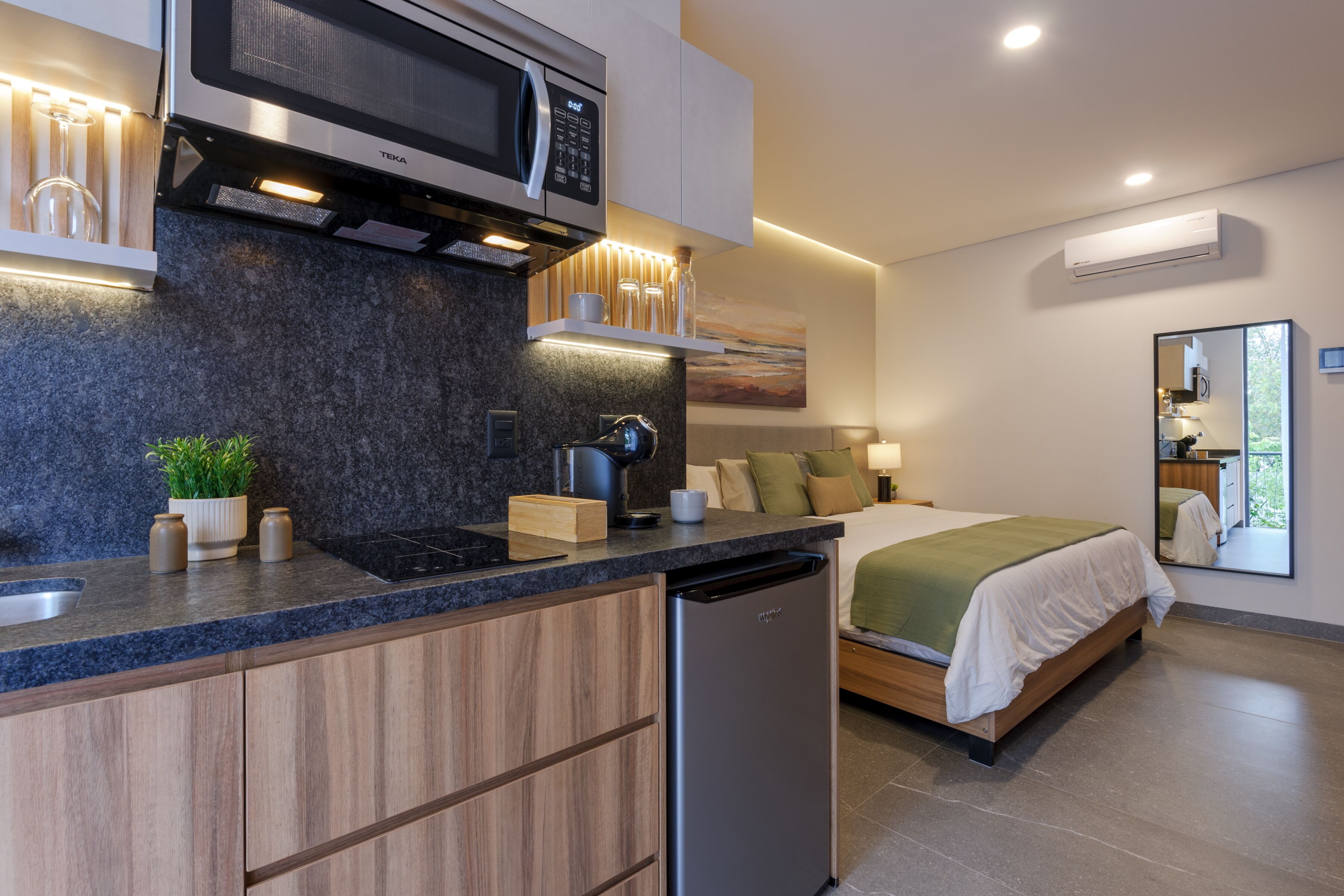 A modern kitchen with a built-in microwave, a dishwasher, and a countertop with a plant and a coffee maker.