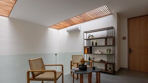 A modern room with a glass partition, two wicker chairs, a round table, and a black bookshelf. - Casa Makech (Zapopan)
