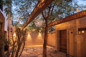 A courtyard with a tree, a brick wall, and a door.