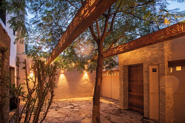 Un patio con un árbol, un muro de ladrillo y una puerta.