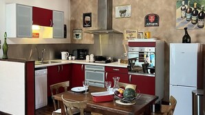 Uma cozinha com vigas de madeira, fogão, pia e mesa de jantar com cadeiras.
