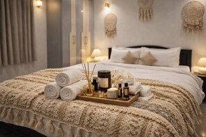 A neatly made bed with rolled towels, a tray of toiletries, and decorative items.