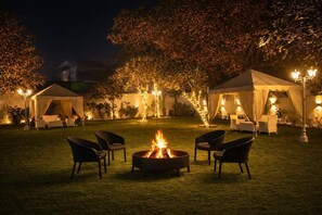A nighttime outdoor setting with a fire pit, chairs, and tents. - Charming 4-bedroom air conditioned bungalow with Pool in South Delhi (Delhi)