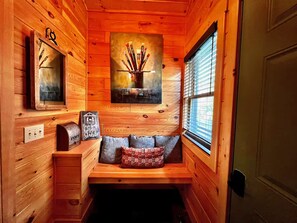 A cozy cabin interior with a wooden bench, a painting of paintbrushes, a mirror, and a small table with a sign. - New Log Cabin-Elevator-HotTub-Firepit-Near Ski Resorts-Grandfather Mtn View (Banner Elk)