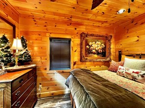 Een houten chalet interieur met een bed, een kapstok, een kerstboom en een lijstwerk schilderij.