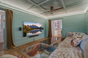 A living room with a flat-screen TV, a ceiling fan, a sofa, and a patterned rug. - 5BR home, walkable, pet friendly w/sauna & theatre (Black Mountain)