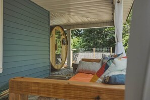 A covered outdoor seating area with a wooden bench, a hammock, and a view of the surrounding greenery. - 5BR home, walkable, pet friendly w/sauna & theatre (Black Mountain)