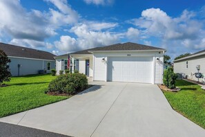Une maison de plain-pied avec un garage, une pelouse bien entretenue et un ciel dégagé.