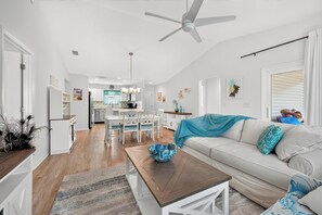 Un salon spacieux avec un canapé blanc, une table basse et un coin repas comprenant une table et des chaises blanches.