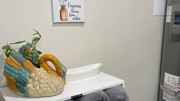 Een badkamer met een witte plank met handdoeken en een decoratief keramiekobject.
