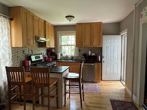 A kitchen with wooden cabinets, a stove, a microwave, and a refrigerator. - Beautiful Family-Friendly 3BR Home in Portland North Back Cove (Portland)