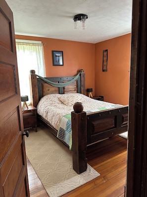 A bedroom with a wooden bed, a nightstand, a lamp, and a ceiling light fixture. - Beautiful Family-Friendly 3BR Home in Portland North Back Cove (Portland)