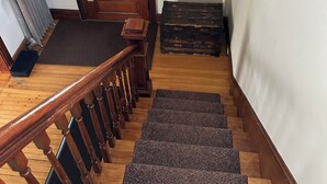 A wooden staircase with a handrail, a radiator, and a door leading to an outdoor area. - Beautiful Family-Friendly 3BR Home in Portland North Back Cove (Portland)