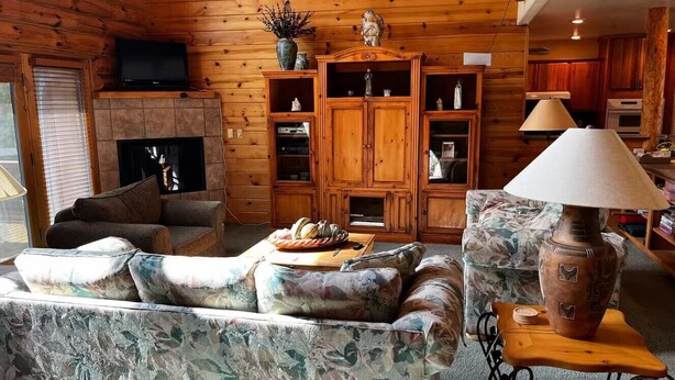 A cozy living room with a fireplace, wooden cabinets, and a television. - Log Cabin in Kirkland, Arizona (Kirkland)