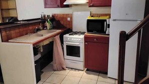 Une cuisine de taille réduite équipée d’une cuisinière, d’un évier, d’un four à micro-ondes et d’un réfrigérateur.