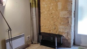 Une pièce avec un radiateur, un banc noir et un mur en pierre.