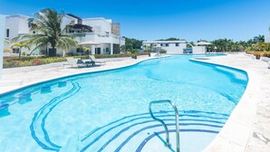 Une piscine avec une eau d’un bleu limpide, un escalier pour y accéder et des chaises longues.