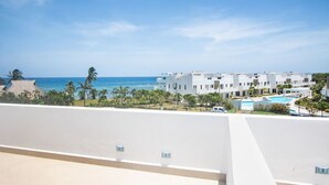 A resort with a pool, white buildings, and a view of the ocean.