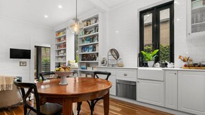 A modern kitchen with white cabinetry, a wooden dining table, and a built-in bookshelf. - Your Richmond Home: Calm, Character, Walkable (Richmond)