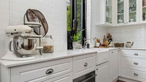 A modern kitchen with white cabinetry, a stand mixer, and a window with a view of greenery. - Your Richmond Home: Calm, Character, Walkable (Richmond)